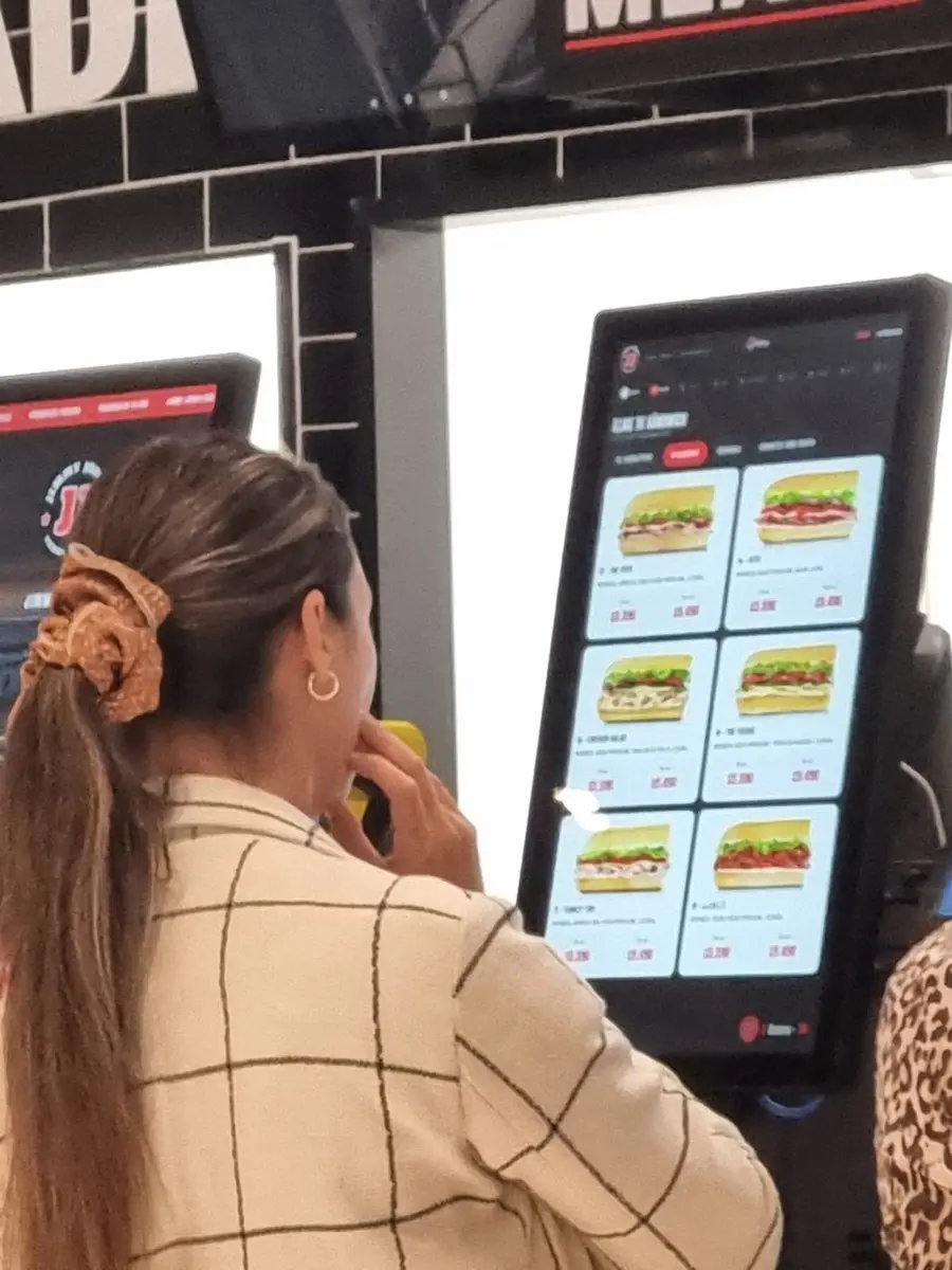 Cliente usando la pantalla táctil de un tótem de autoservicio